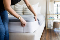 Person tucking sheets into a Better Bedder on a bed in a bedroom setting.